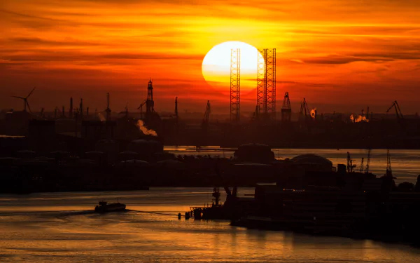 Sunset over Rotterdam harbor with silhouettes of wind turbines, cranes, and industrial structures, captured in striking 4K Ultra HD photography.