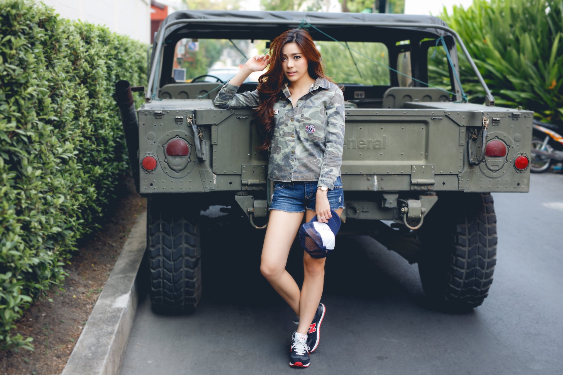Asian woman model in khaki jacket and shorts poses confidently in front of a rugged Jeep, captured in 4K Ultra HD for a stylish PC desktop wallpaper background.