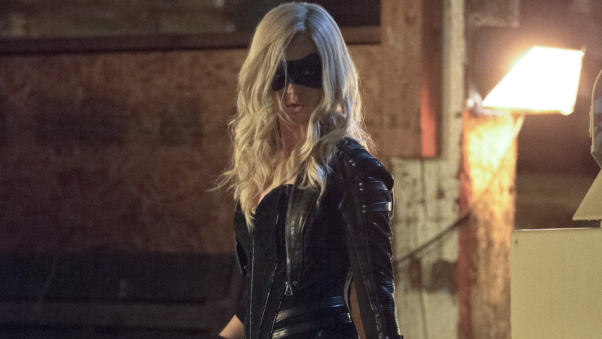 Caity Lotz as Black Canary in a dramatic scene from the TV show Arrow. The image showcases her in a sleek black outfit, set against a moody backdrop.