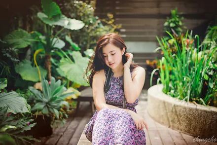 A Taiwanese woman in a patterned dress sits thoughtfully in a lush garden. The image, featuring Asian model Chén Sīyǐng, serves as an HD desktop wallpaper and background.