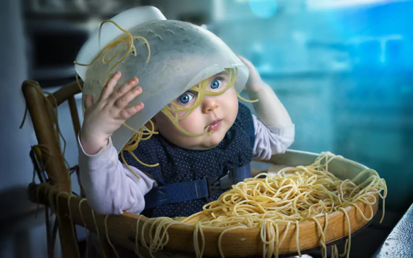 A humorous HD desktop wallpaper featuring a baby with spaghetti on their head and in a high chair, captured in vibrant photography style.