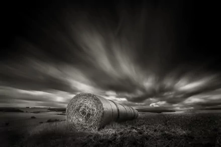 Black and white HD desktop wallpaper of a dramatic cloudscape over a rural field with a large haystack in the foreground, showcasing nature’s serene yet powerful landscape.