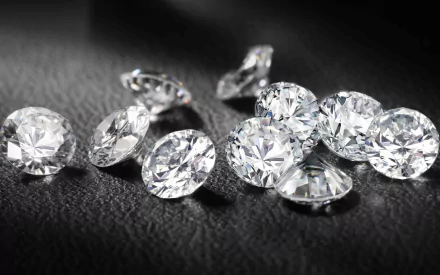 A collection of sparkling diamonds on a dark surface, shown in high-definition. This nature-inspired desktop wallpaper exudes elegance and luxury.