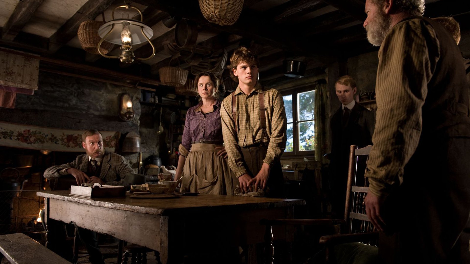 Scene from the movie War Horse showing characters in period clothing gathered in a dimly lit rustic room, presented as an HD PC desktop wallpaper and background.