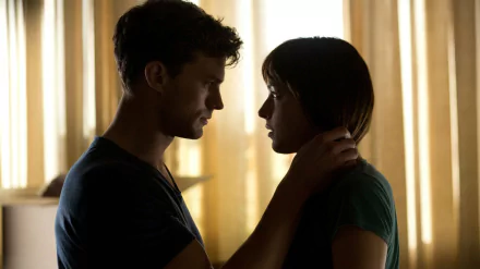 A HD desktop wallpaper featuring Jamie Dornan and Dakota Johnson in a scene from the movie Fifty Shades of Grey, with Dornan holding Johnson's neck in an intimate moment.