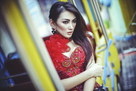 HD desktop wallpaper of an Asian brunette model with brown eyes, wearing an ornate red dress, posed against a blurred bokeh background.