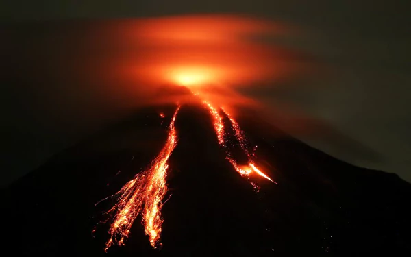 A striking HD wallpaper of an active volcano, featuring flowing lava and billowing smoke against a dark backdrop, capturing the raw power of nature.
