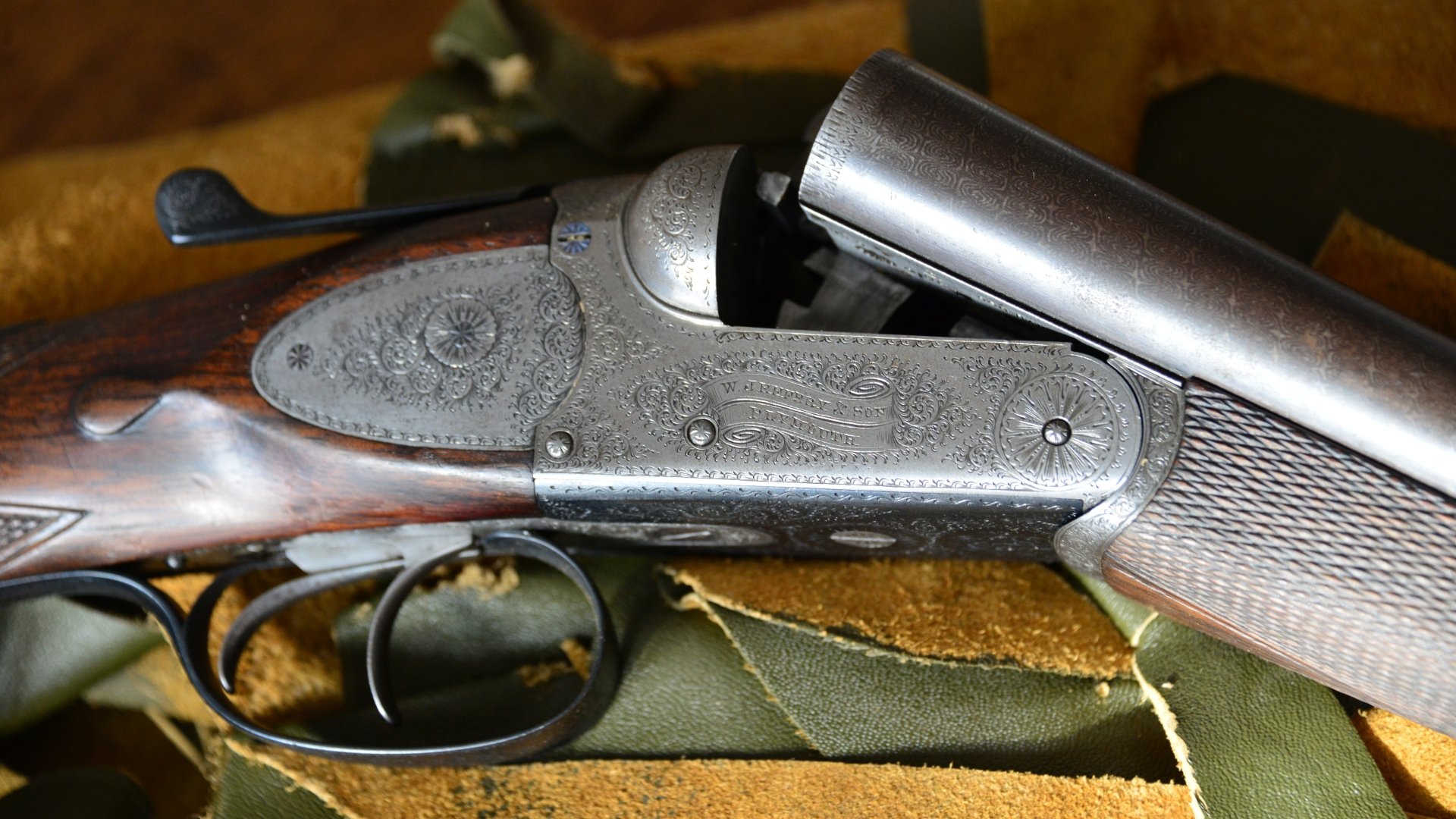 Close-up of an engraved man-made shotgun displayed on fabric, captured in 4K Ultra HD for a detailed PC desktop wallpaper background.