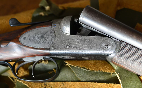 Close-up of an engraved man-made shotgun displayed on fabric, captured in 4K Ultra HD for a detailed PC desktop wallpaper background.