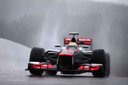 A McLaren F1 racing car speeds through a rainy track, showcasing its sleek design and powerful presence, featured as an HD PC desktop wallpaper and background.
