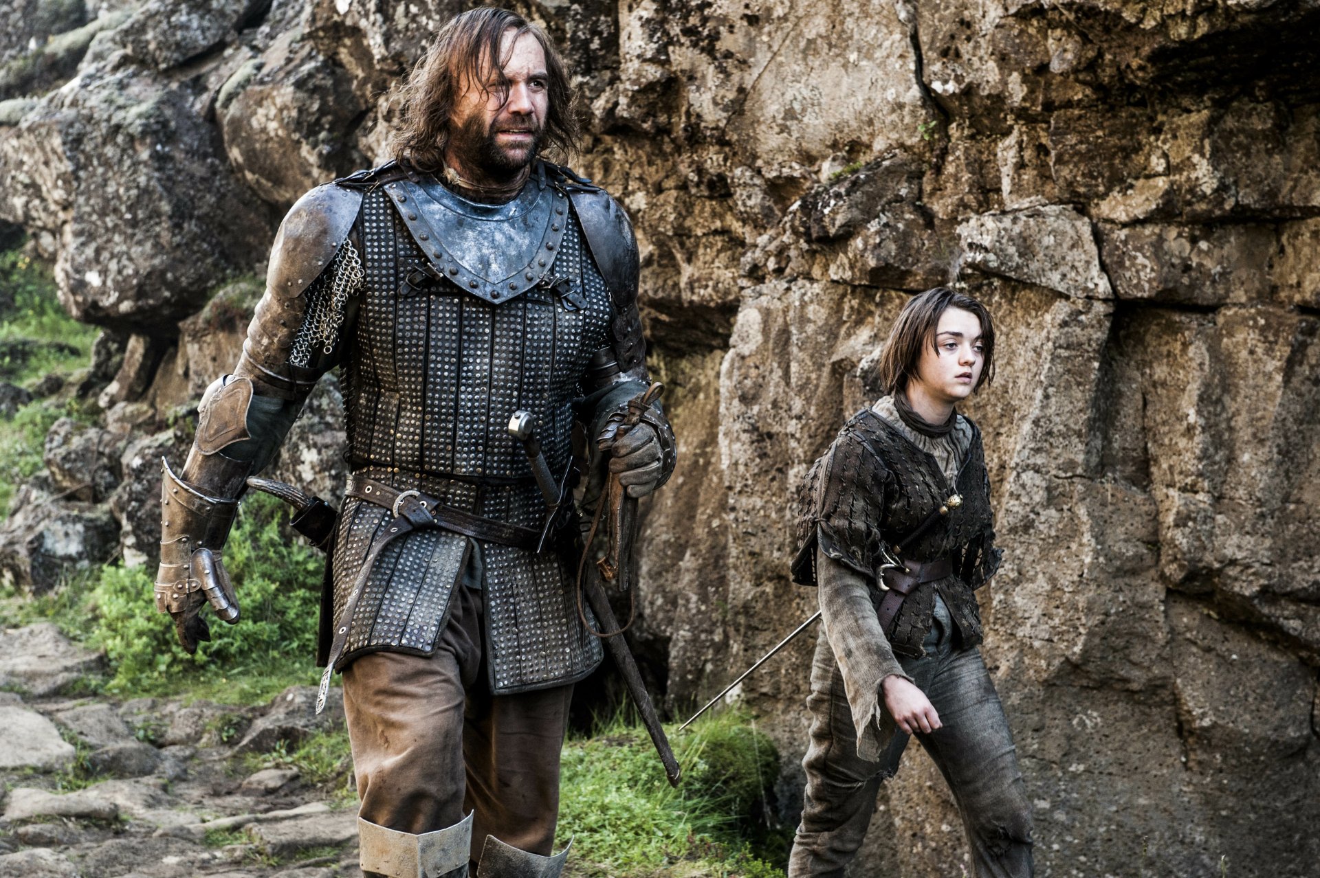 Rory McCann as Sandor Clegane and Maisie Williams as Arya Stark from Game of Thrones walk through rocky terrain in this 4K Ultra HD PC desktop wallpaper.