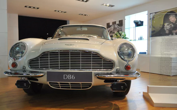 Front view of a white Aston Martin DB6 vehicle in a showroom — 2K Quad HD PC desktop wallpaper and background.