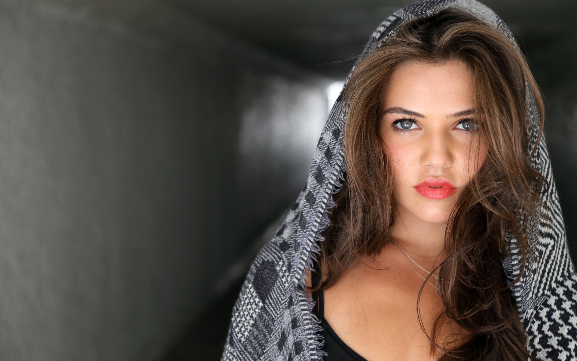 HD PC desktop wallpaper featuring celebrity Danielle Campbell with striking blue eyes, wearing a patterned hooded garment in a softly lit tunnel background.