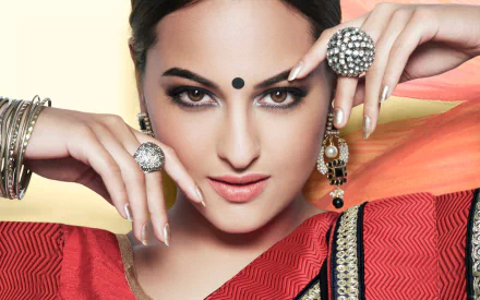 HD desktop wallpaper featuring celebrity Sonakshi Sinha, who is adorned in traditional attire and jewelry, with an elegant pose and confident expression.
