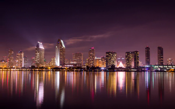 Nighttime cityscape of San Diego with illuminated skyscrapers reflecting on calm water, captured in 4K Ultra HD for a sharp and vibrant desktop background.