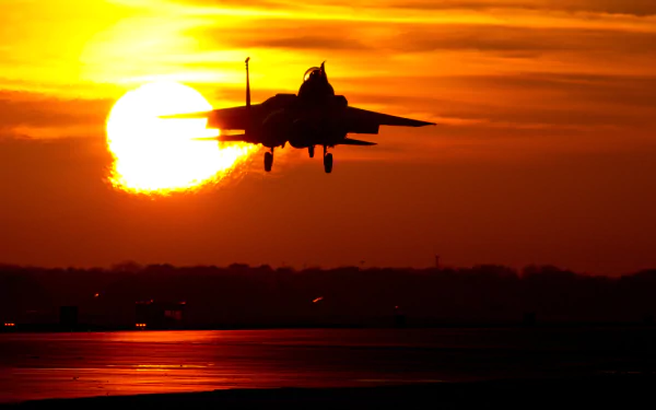 A McDonnell Douglas F-15E Strike Eagle silhouetted against a vibrant sunset, creating a striking military-themed HD PC desktop wallpaper.