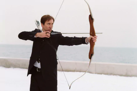 Nicolas Cage in a scene from The Weather Man, poised with a bow and arrow against a snowy backdrop, captured in a striking HD desktop wallpaper.