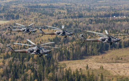 HD desktop wallpaper featuring four Mil Mi-28 military helicopters flying over a dense forest landscape.