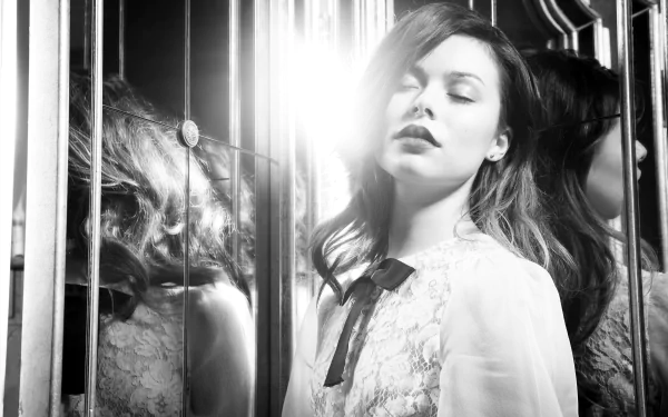 Black and white 4K Ultra HD desktop wallpaper of celebrity Miranda Cosgrove with soft lighting and reflective glass panels creating an artistic, moody atmosphere.