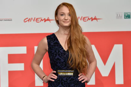 Sophie Turner poses confidently at a film event, wearing a stylish dress, showcasing her long red hair, set against a vibrant cinema-themed backdrop. 4K Ultra HD wallpaper.
