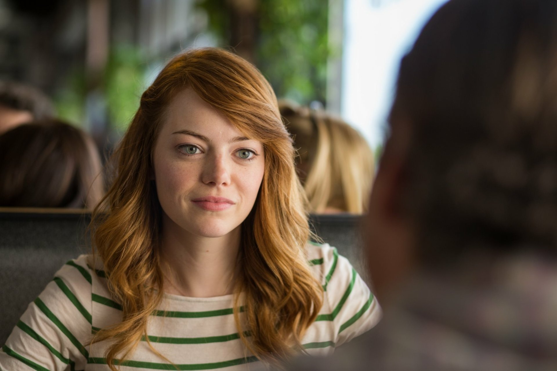 Red-haired woman in a striped shirt smiles across a diner booth — HD movie still from Irrational Man, desktop wallpaper.