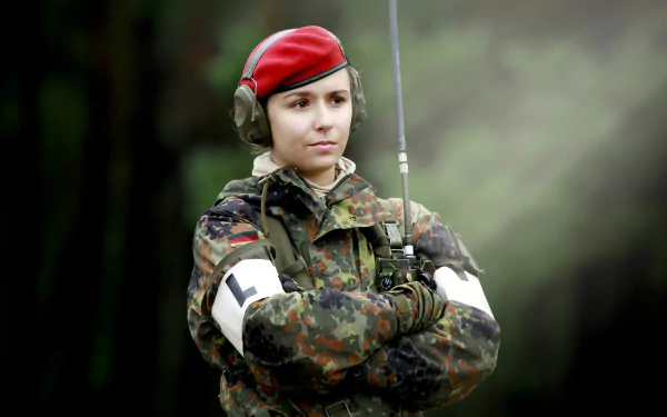 4K Ultra HD desktop wallpaper featuring a female soldier in military camouflage uniform and red beret with radio headset, standing confidently in an outdoor setting.