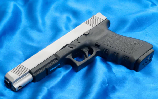 High-definition desktop wallpaper featuring a Glock pistol on a vibrant blue fabric background.