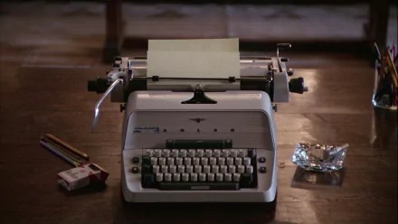 HD PC desktop wallpaper from the movie The Shining featuring a vintage typewriter with a blank sheet of paper, pencils, and an ashtray on a wooden table.