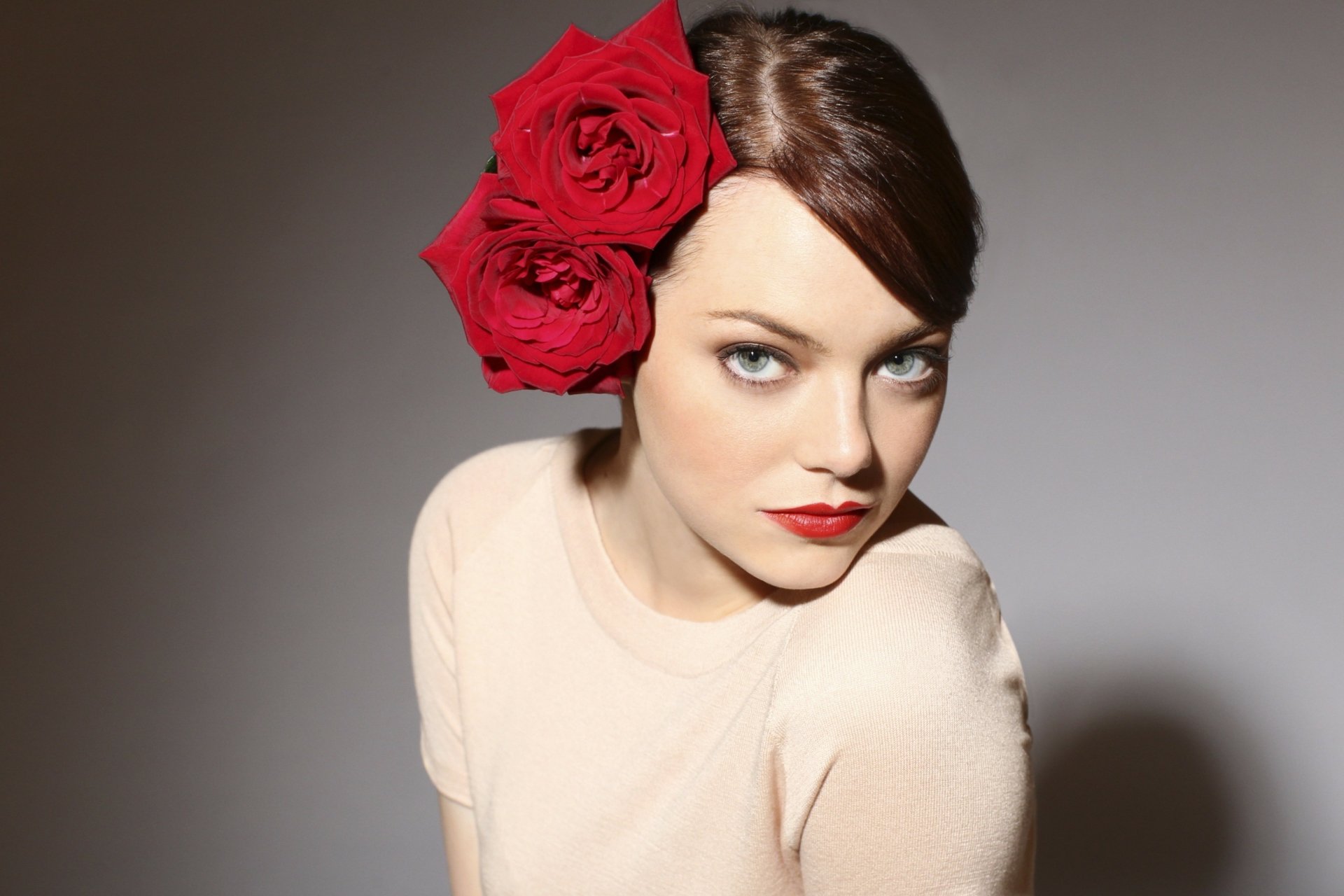 4K Ultra HD desktop wallpaper featuring celebrity Emma Stone with red roses in her hair, wearing a light beige top against a neutral background.