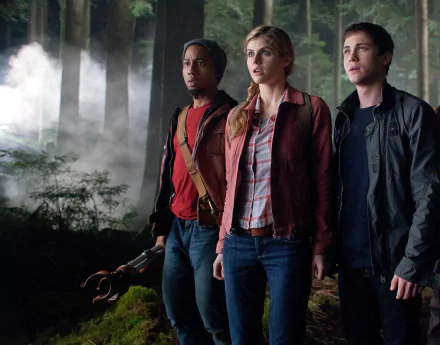 Brandon T. Jackson, Alexandra Daddario, and Logan Lerman stand together in a forest scene from Percy Jackson: Sea of Monsters, surrounded by mist and suspenseful atmosphere.