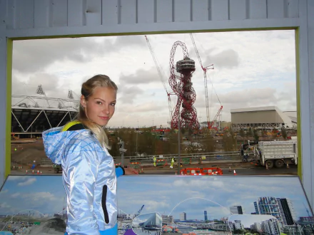 HD PC desktop wallpaper: a female athlete in a blue jacket smiles in front of a sports-themed cityscape featuring an Olympic stadium and observation tower.