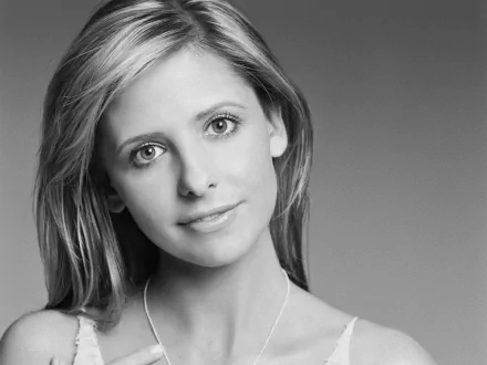 Black-and-white close-up portrait of a blonde woman smiling softly against a smooth gray background, HD PC desktop wallpaper.
