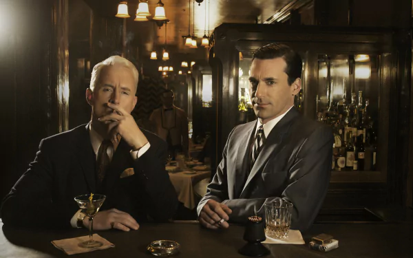A 4K Ultra HD TV show wallpaper of Mad Men featuring two men in suits seated at a dimly lit bar, embodying the show's classic, stylish 1960s atmosphere.