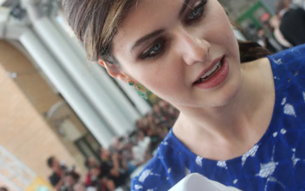 A close-up of Alexandra Daddario, wearing a blue outfit, with a crowd in the background. This HD image serves as a vibrant desktop wallpaper.