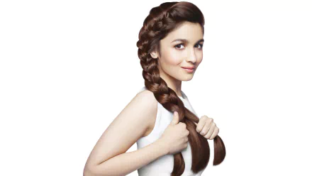 A smiling woman with brown eyes and long brown hair braided over her shoulder. This HD desktop wallpaper features celebrity Alia Bhatt with a serene expression.