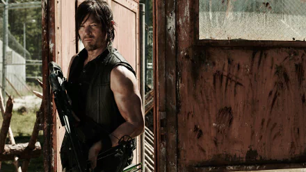Daryl Dixon, portrayed by Norman Reedus, stands confidently at an old doorway, exuding strength and resilience from the TV show The Walking Dead in this HD desktop wallpaper.
