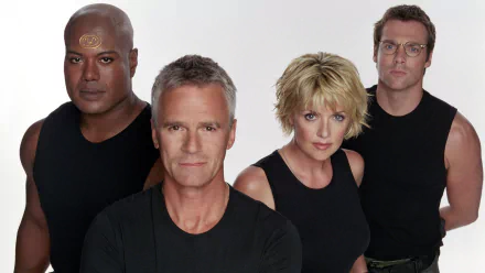 HD PC desktop wallpaper: four cast members in black tops posed against a white background promoting the TV sci‑fi show Stargate SG‑1.