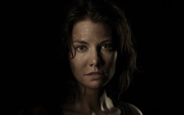 A close-up of Maggie Greene, portrayed by Lauren Cohan, from the TV show The Walking Dead, highlighting her intense expression against a dark background.
