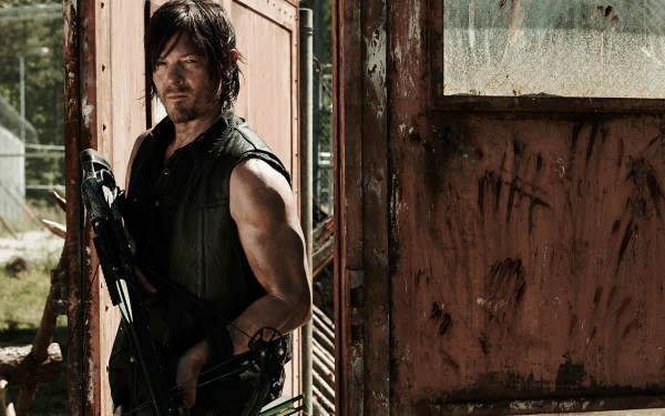 Daryl Dixon, portrayed by Norman Reedus, stands confidently at an old doorway, exuding strength and resilience from the TV show The Walking Dead in this HD desktop wallpaper.