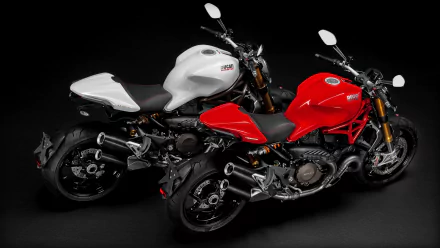 HD PC desktop wallpaper showcasing two Ducati Monster motorcycles, one in white and the other in red, against a black background.