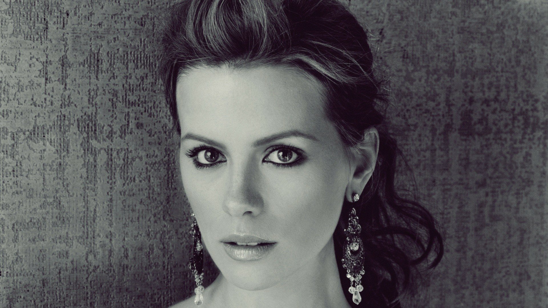 HD desktop wallpaper featuring a close-up black and white portrait of celebrity Kate Beckinsale with elegant earrings against a textured background.