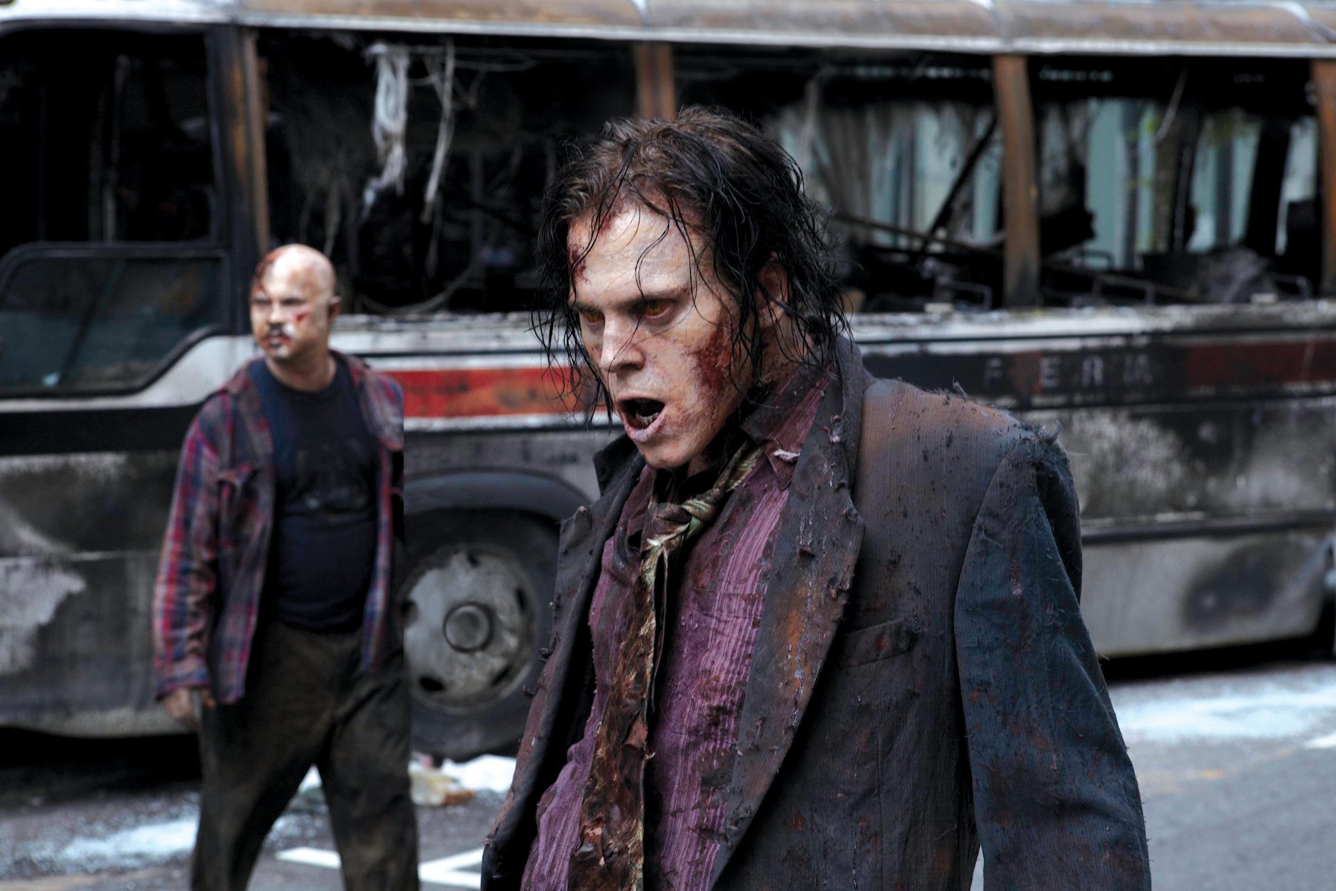 A 4K Ultra HD desktop wallpaper featuring intense characters from the TV show The Walking Dead standing near a burnt-out bus in a post-apocalyptic setting.