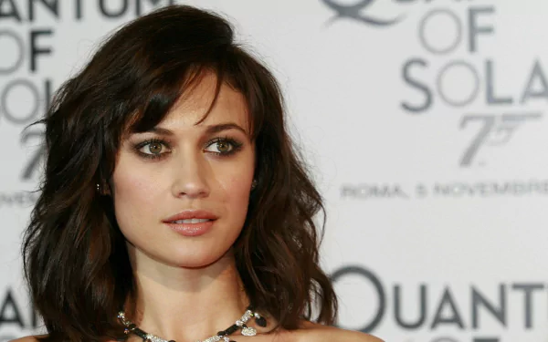 Olga Kurylenko poses gracefully at a promotional event for Quantum of Solace, showcasing her elegance in this high-definition desktop wallpaper.