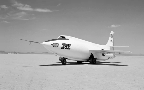 Black and white 4K Ultra HD wallpaper of the military Bell X-1 aircraft on a desert runway under a partly cloudy sky.