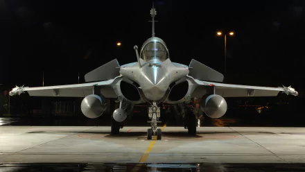 A striking HD wallpaper featuring a Dassault Rafale military aircraft, prominently displayed with its sleek design and powerful stance under dim lighting.