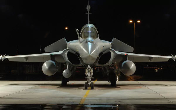 A striking HD wallpaper featuring a Dassault Rafale military aircraft, prominently displayed with its sleek design and powerful stance under dim lighting.