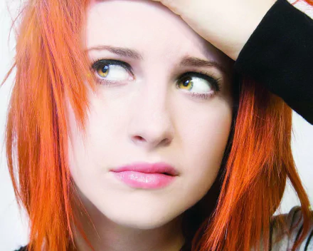 HD PC desktop wallpaper featuring a close-up of Hayley Williams with vibrant orange hair and an expressive look, capturing a music-inspired mood.