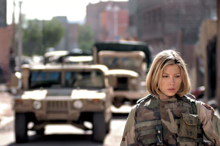 Female soldier from the movie Home of the Brave in camouflage, walking past military Humvees on a damaged city street — 2K Quad HD PC desktop wallpaper/background.