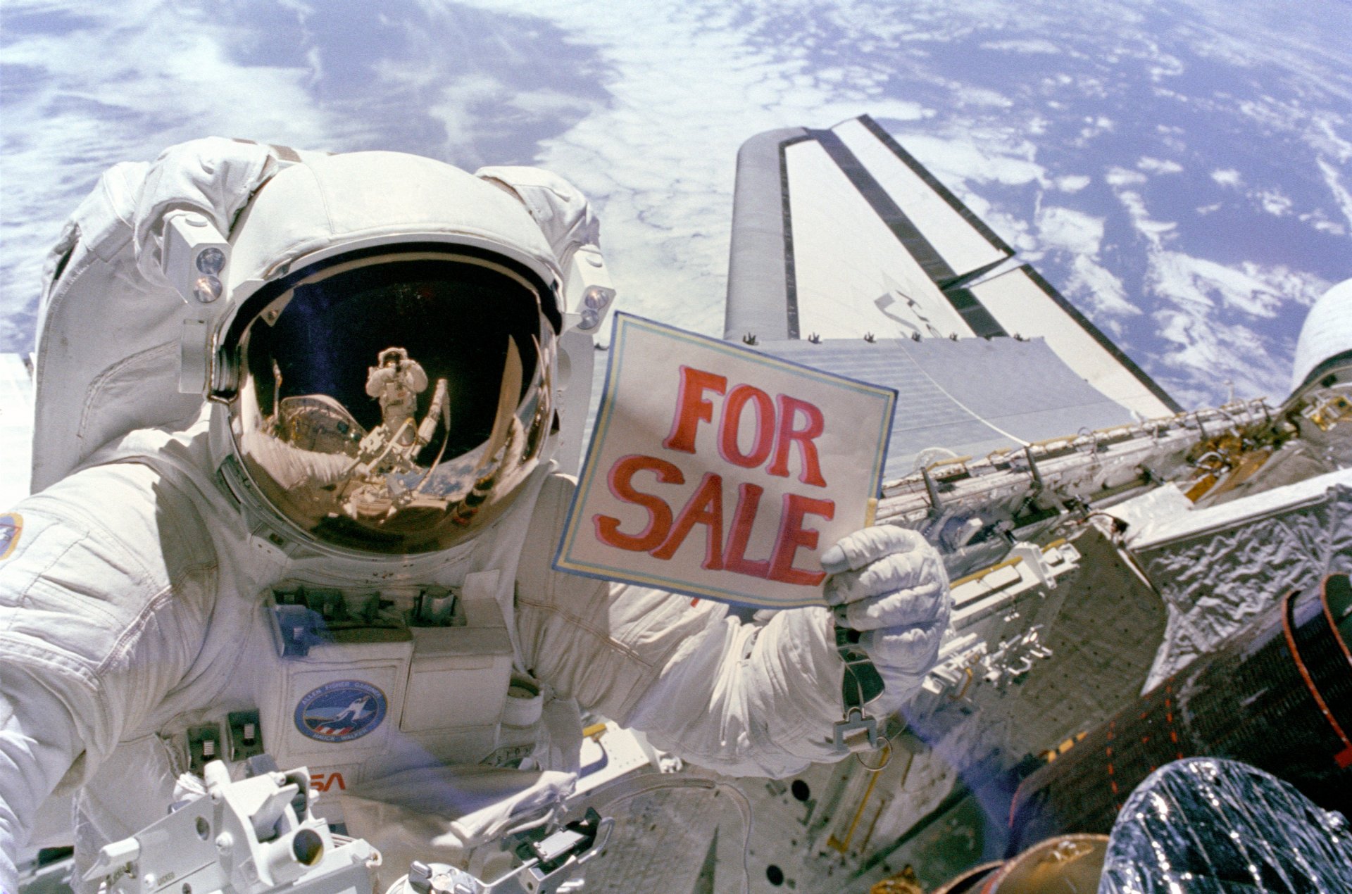 HD desktop wallpaper showing a NASA astronaut in space near a satellite, holding a FOR SALE sign with Earth visible in the background.