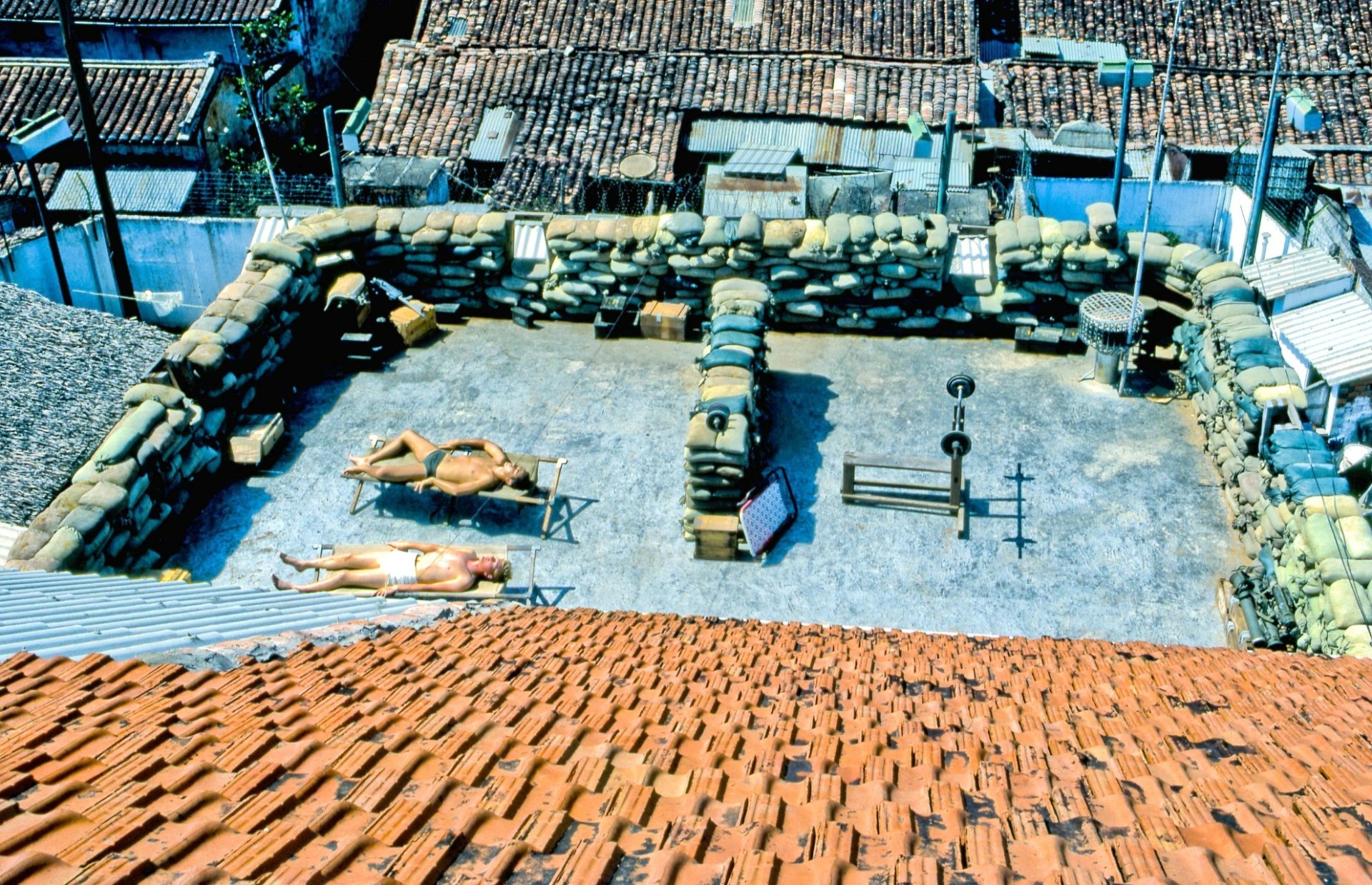 HD desktop wallpaper depicting a military compound from the Vietnam War, featuring sandbag fortifications and soldiers resting inside the secured perimeter.